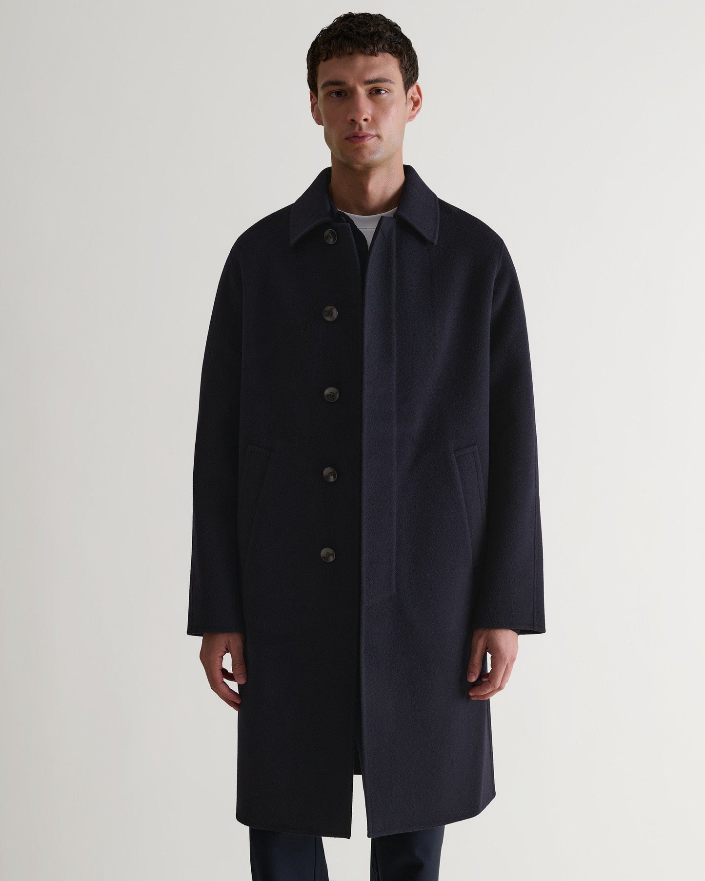Full length front view of man wearing Rise & Fall's navy cashmere merino double-faced coat. 