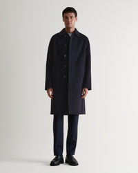 Full length front view of Rise & Fall's navy cashmere merino double-faced coat. Paired with black trousers and shoes. 