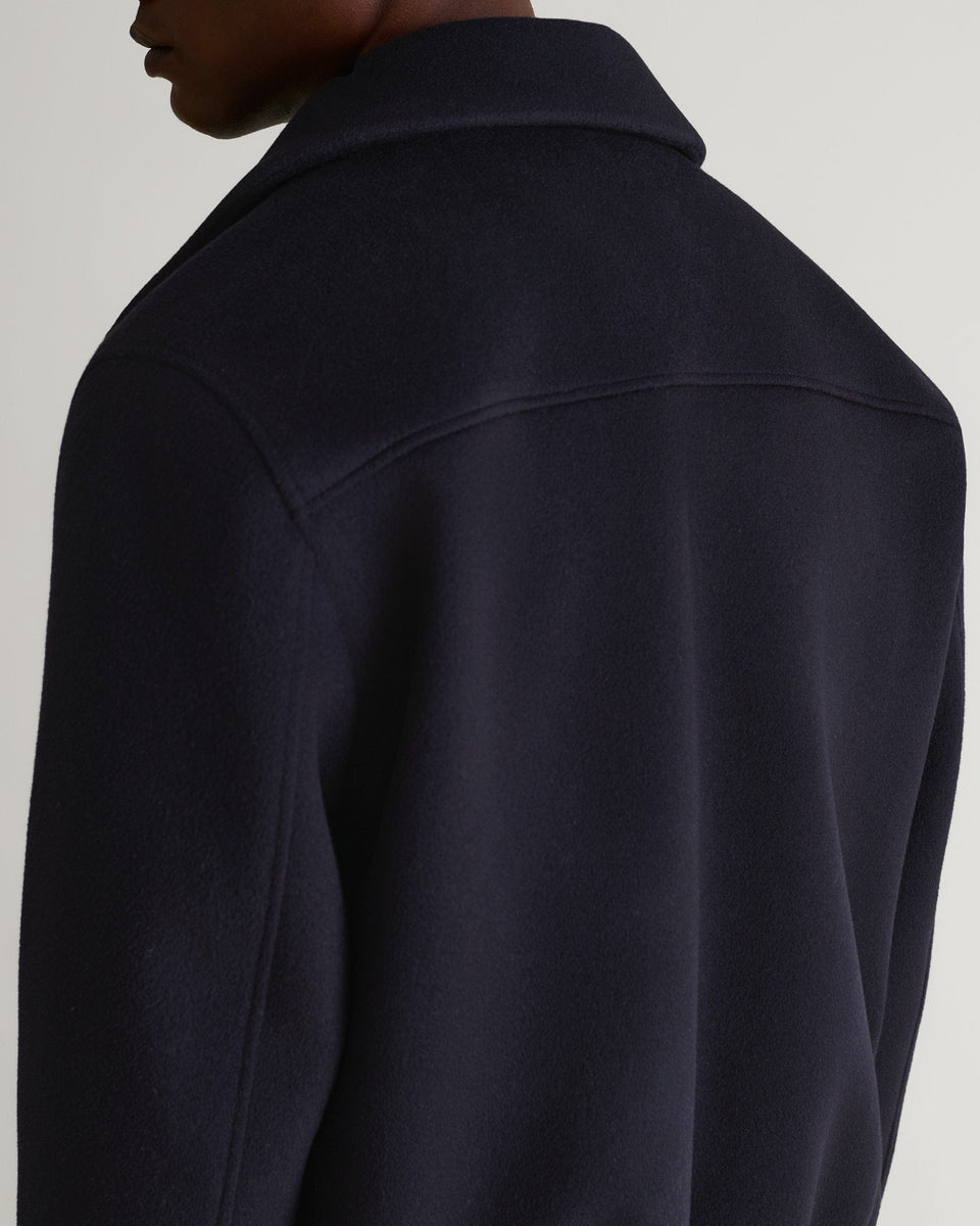 Close up back view of man wearing Rise & Fall's navy wool bomber jacket with shearling collar.