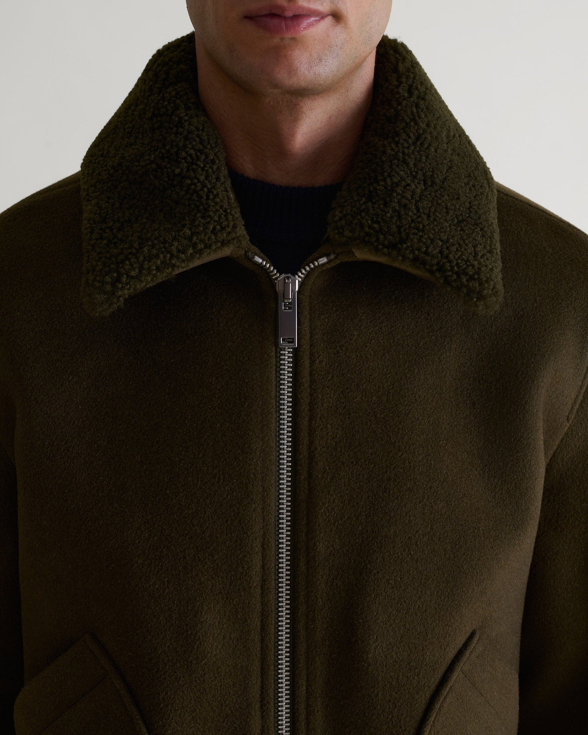 Close up of Rise & Fall's olive wool bomber jacket with shearling collar. Top half.