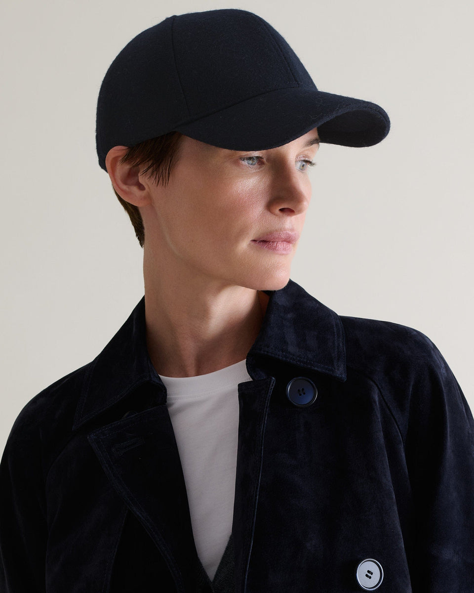 Side view of woman wearing Rise & Fall's navy cashmere merino wool baseball cap.
