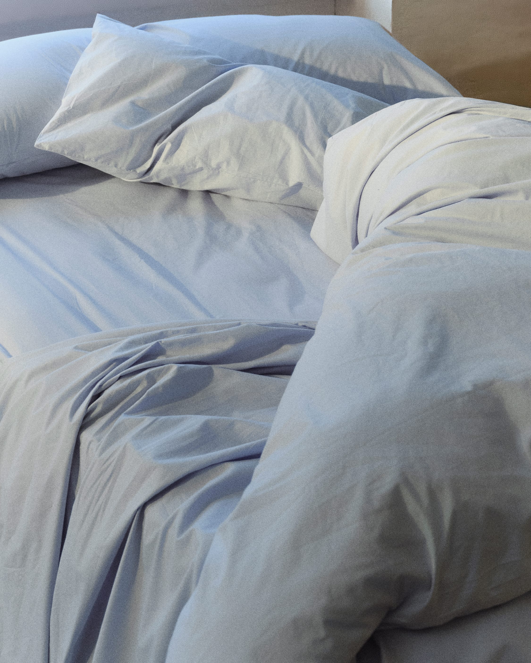 An unmade bed in light blue.