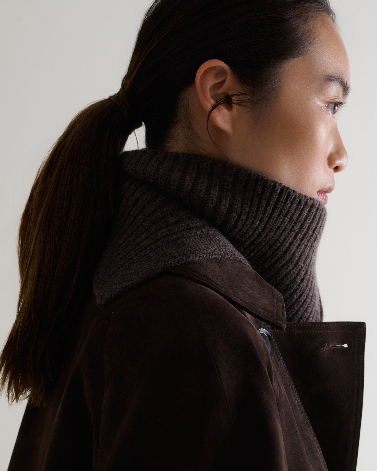 Side view of woman wearing chocolate cashmere merino ribbed collar with chocolate suede coat