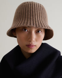 Close up of woman wearing Rise & Fall's beige merino wool ribbed knit bucket hat.