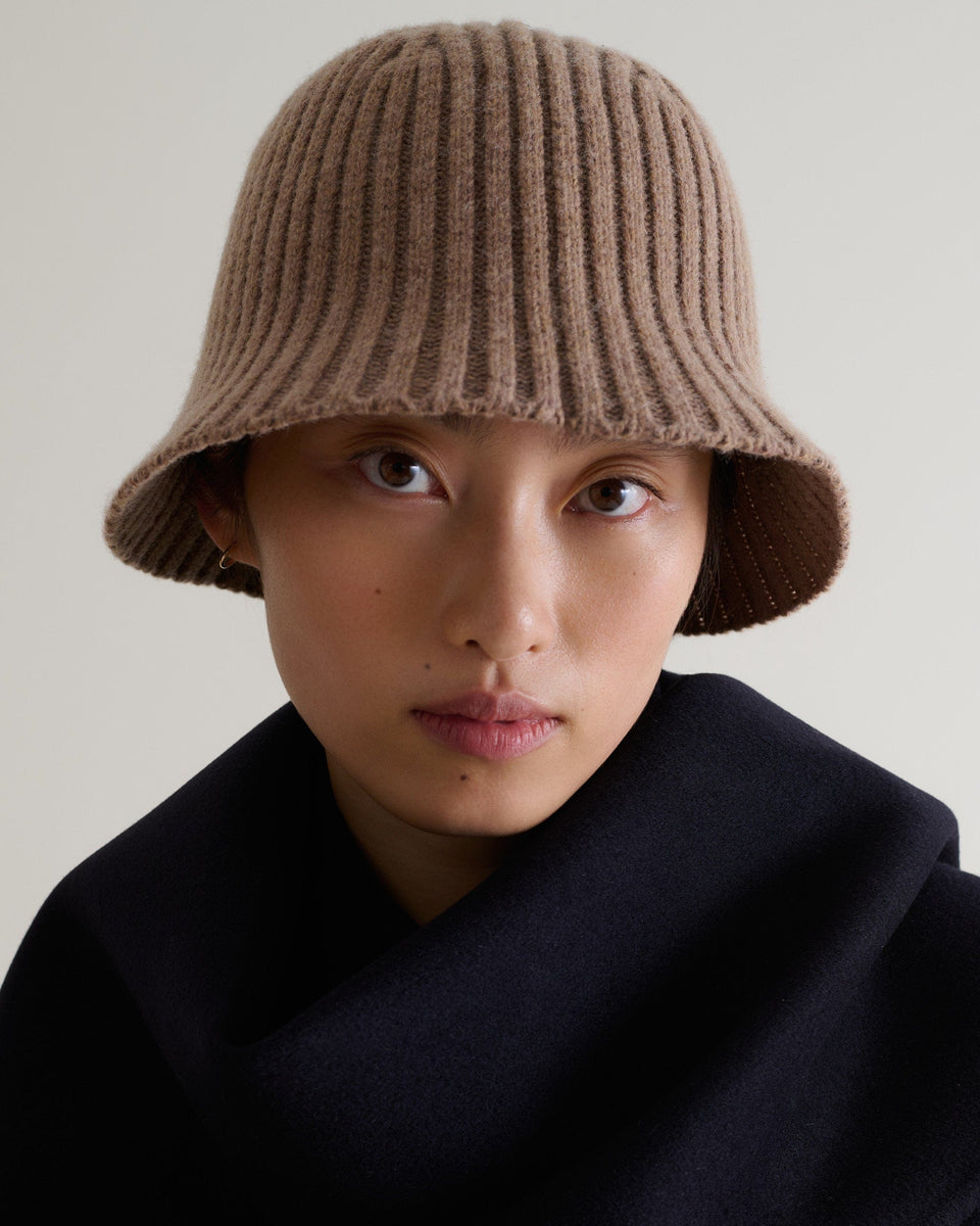 Close up of woman wearing Rise & Fall's beige merino wool ribbed knit bucket hat.