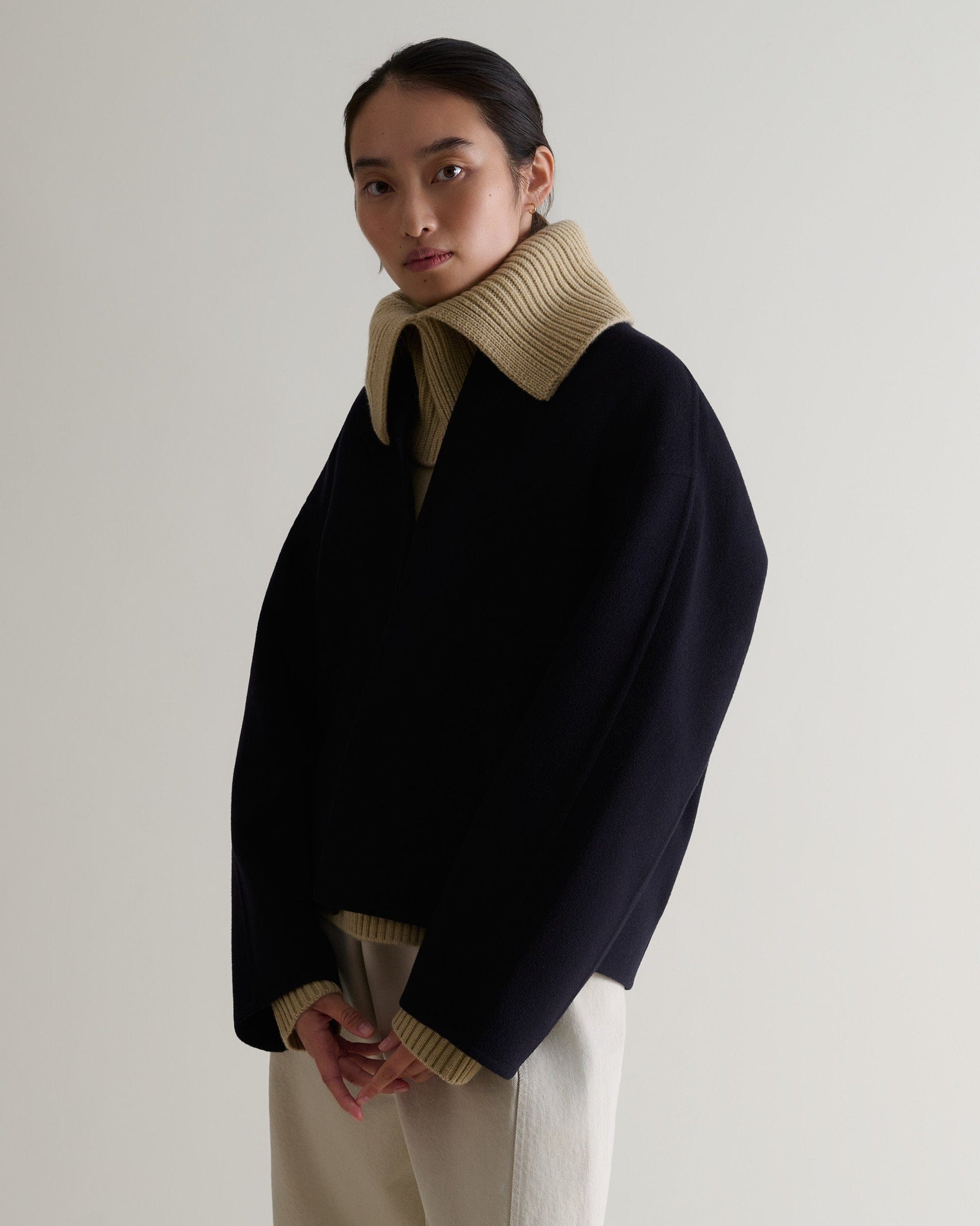 side view of woman wearing twine cashmere merino ribbed collar worn over dark jacket