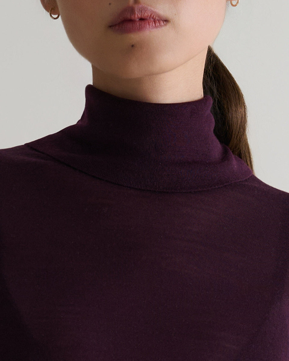 Woman wears Rise & Fall's oxblood superfine merino roll neck jumper. A close up of neckline.